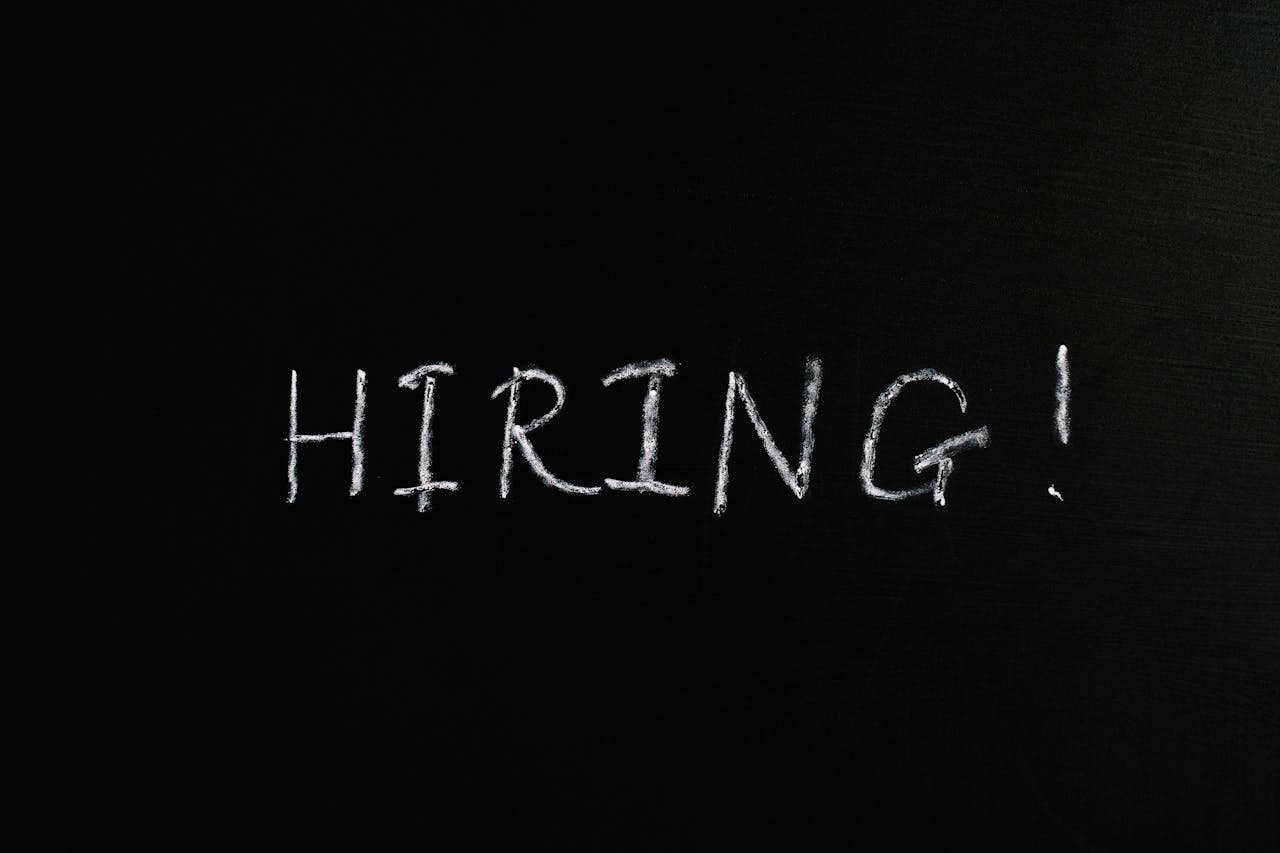 Close-up of the word Hiring! written in white chalk on a blackboard, ideal for recruitment themes.